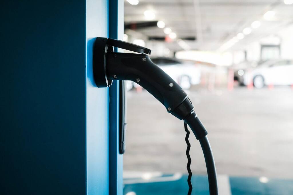 Electric vehicle charging at a public charging station in a parking garage.